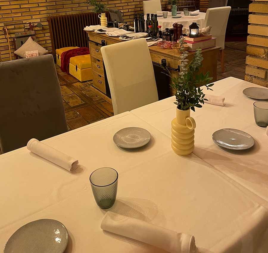 Una mesa con platos y vasos y un jarrón con flores encima.