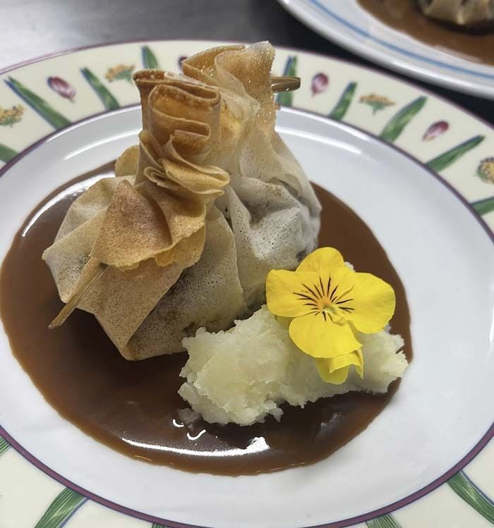 Un primer plano de un plato de comida con una flor encima.