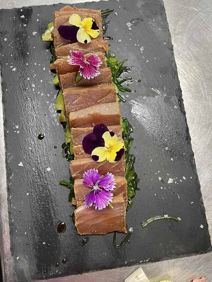 Un primer plano de un plato de comida con flores encima.