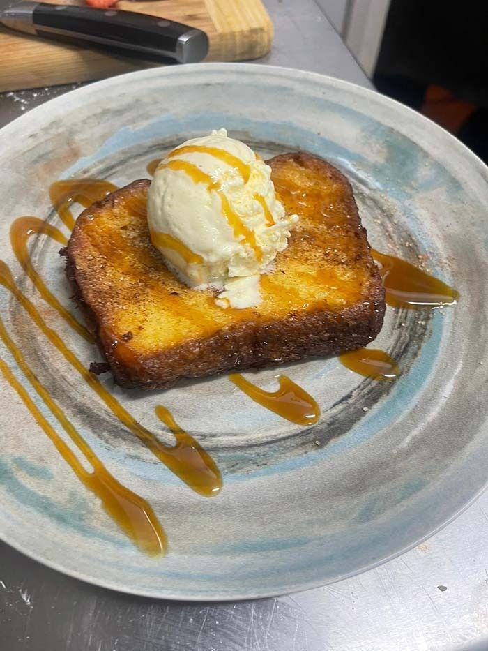 Una rebanada de tostada francesa con helado y salsa de caramelo en un plato.