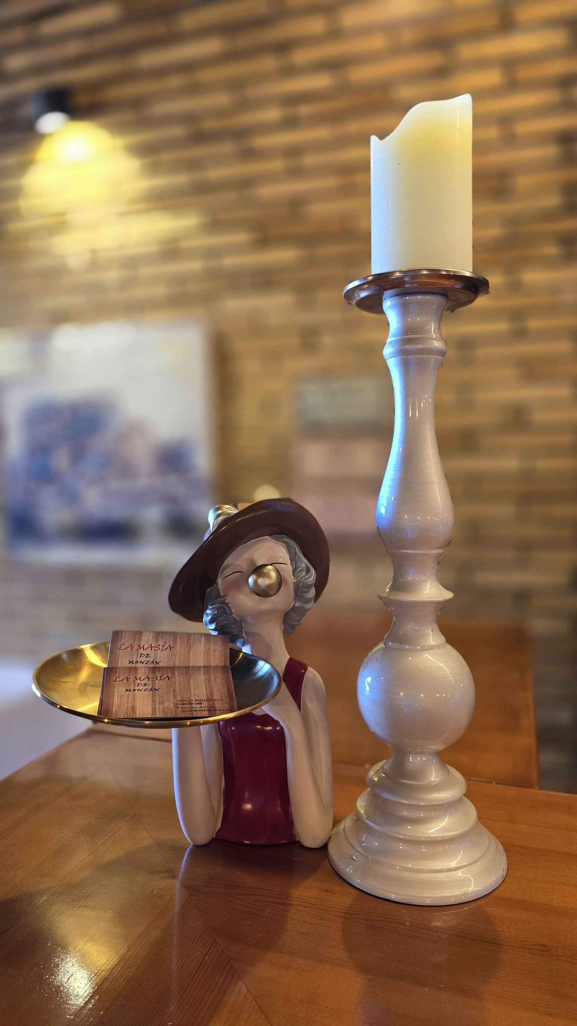 Una figura de una mujer sosteniendo un pastel junto a un candelabro.