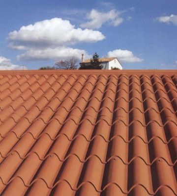 Un techo de tejas rojas con una casa al fondo