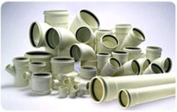 Una pila de tuberías y accesorios blancos sobre una superficie blanca