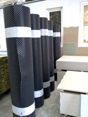 Una fila de rollos de alfombras de goma colocados uno al lado del otro en un almacén.