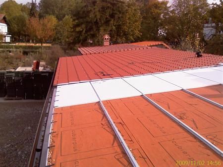 Un techo rojo y blanco con una chimenea al fondo.