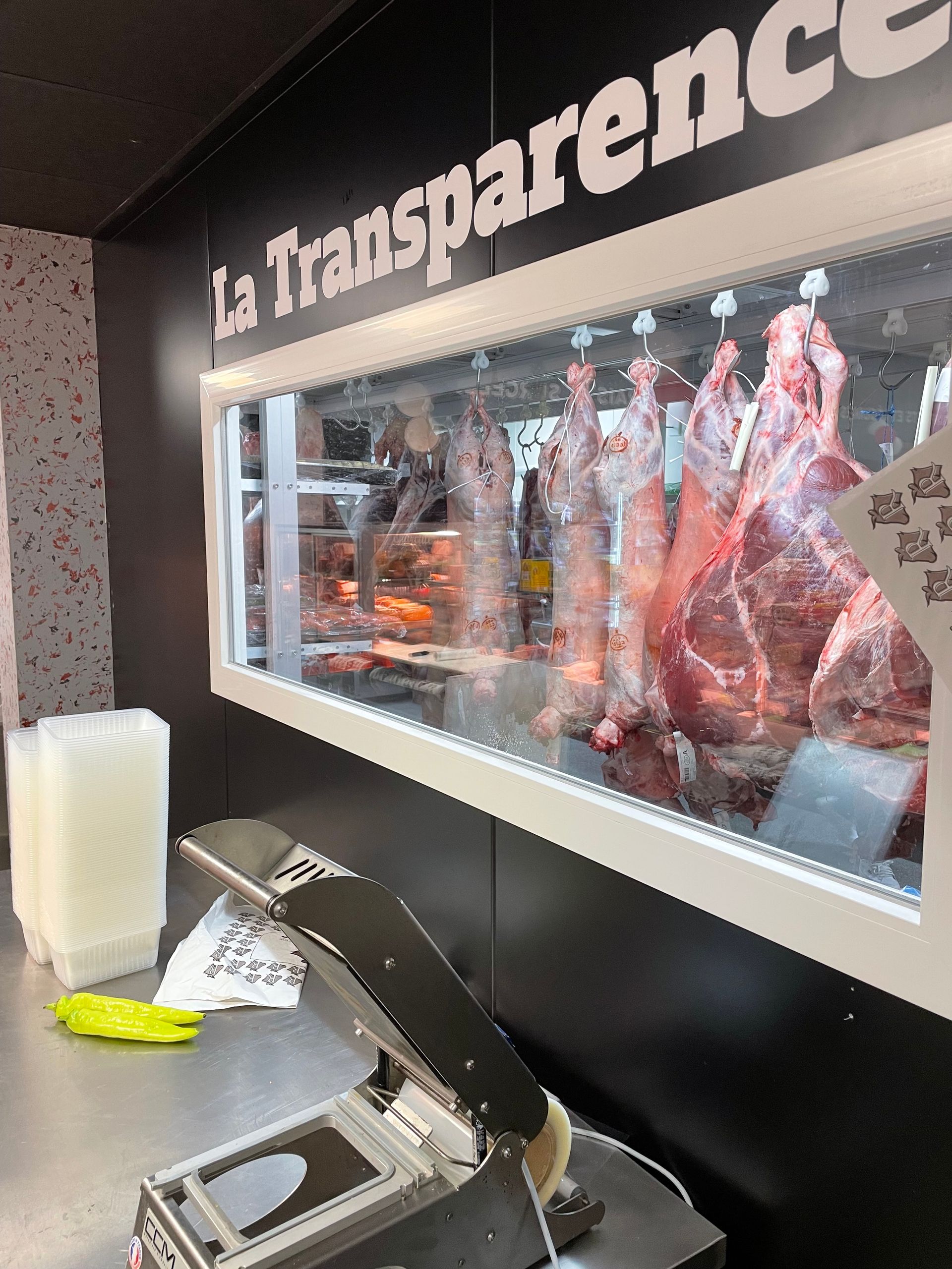 De la viande dans une vitrine réfrigérée face à une machine sur une table
