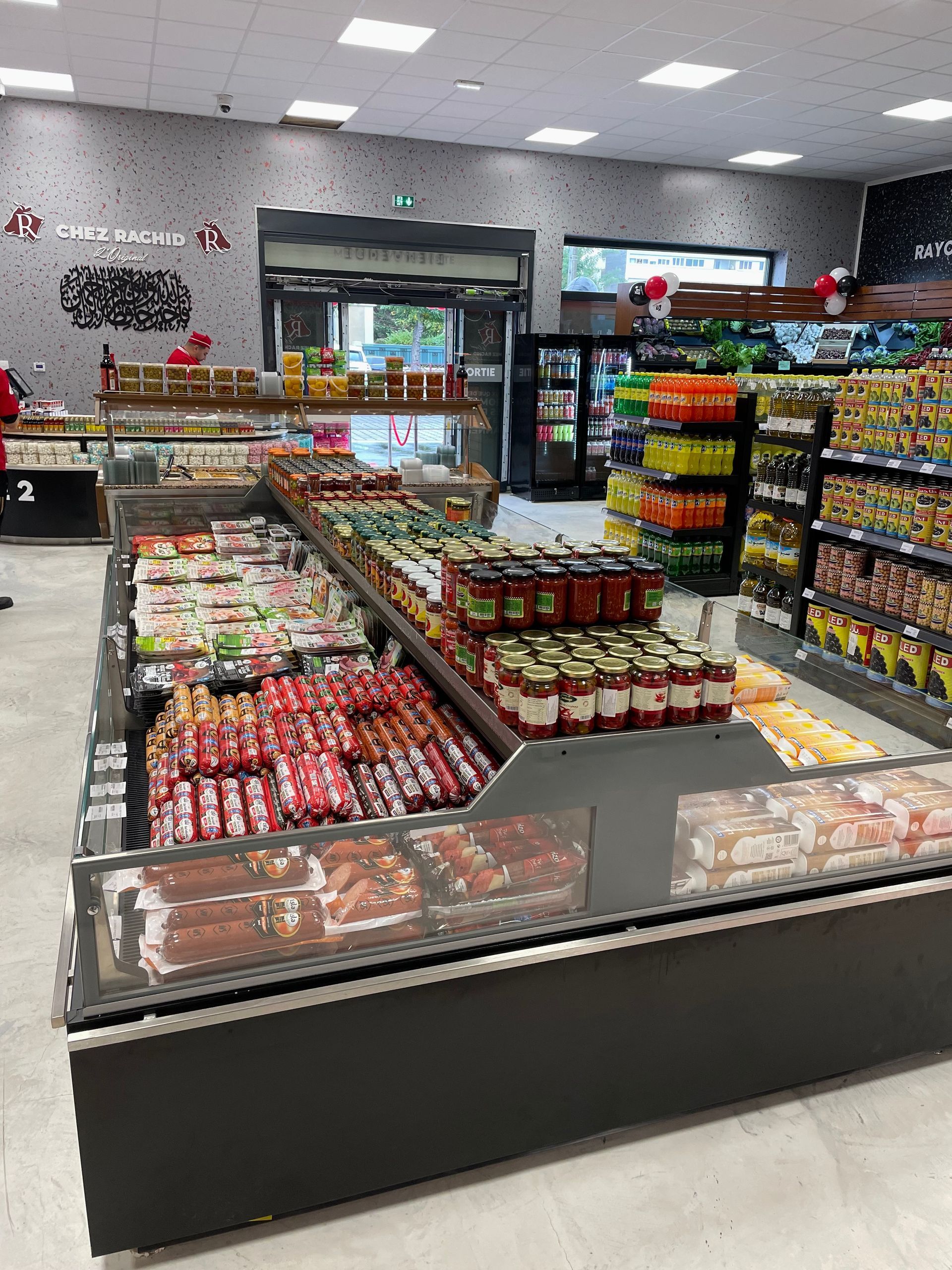 Intérieur d'un supermarché, des vitrines réfrigérées remplies de produits emballés.