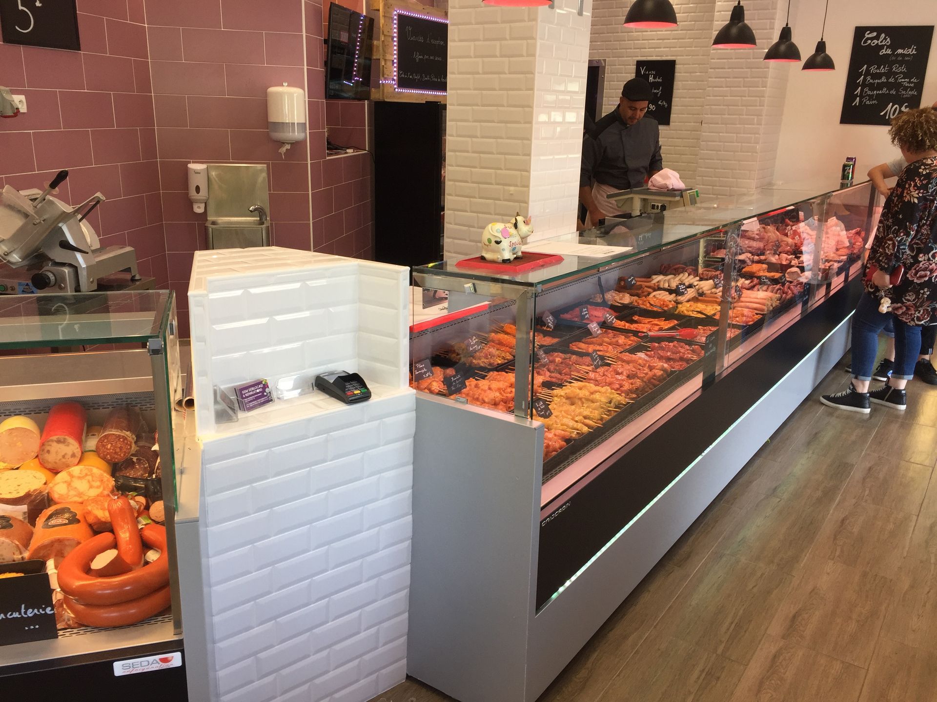 Boucherie : Une vitrine de viandes, un comptoir de service à la clientèle, un boucher découpant la viande.