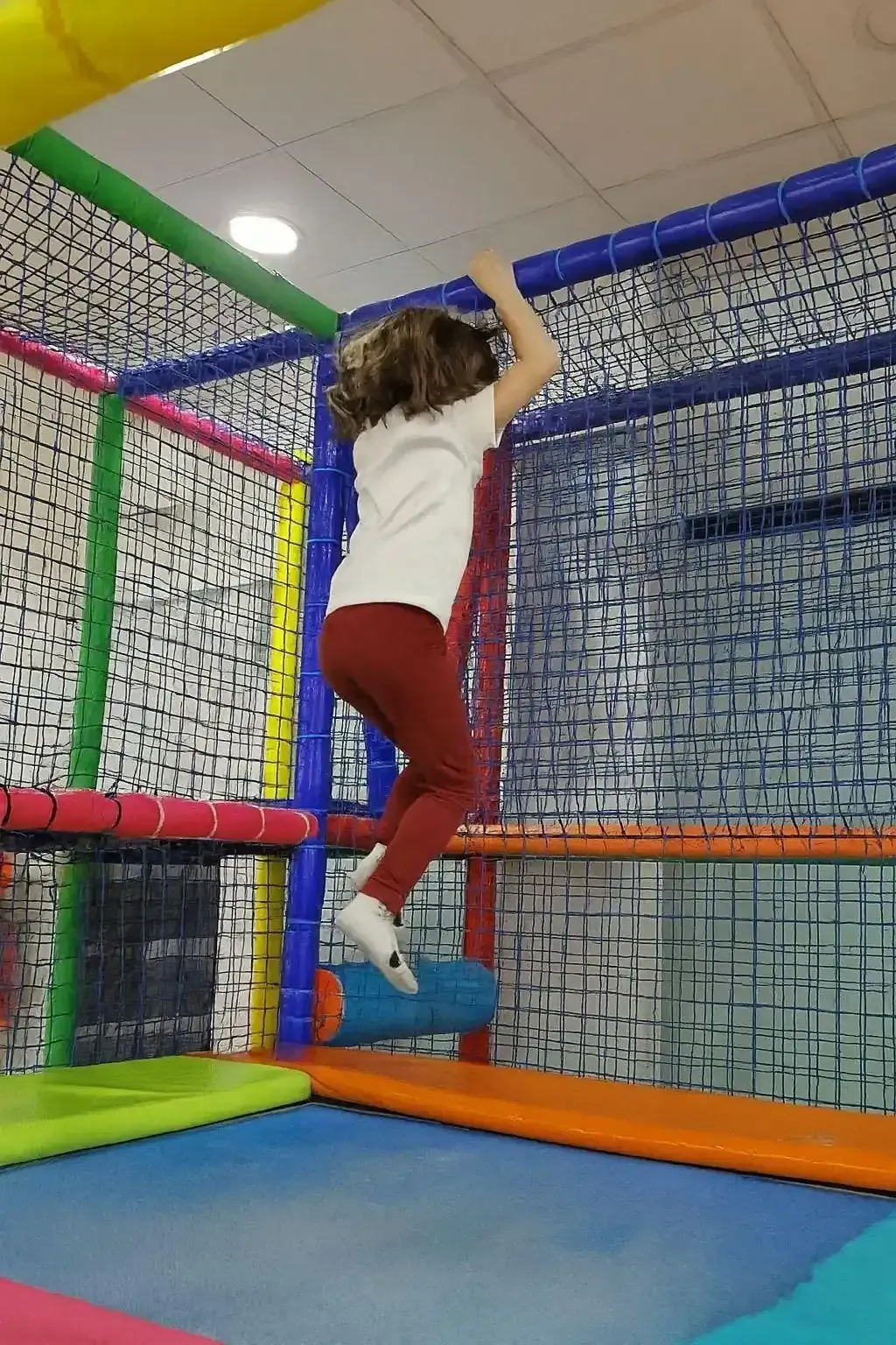 Una persona con una camisa blanca y mallas rojas salta en un trampolín en un 