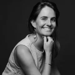 Une photo en noir et blanc d'une femme souriant avec sa main sur son menton.