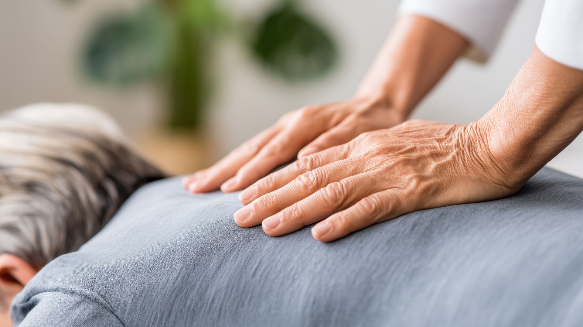 Mains sur le dos, peut-être pour un massage ou un soin. Vêtements gris, peau claire.