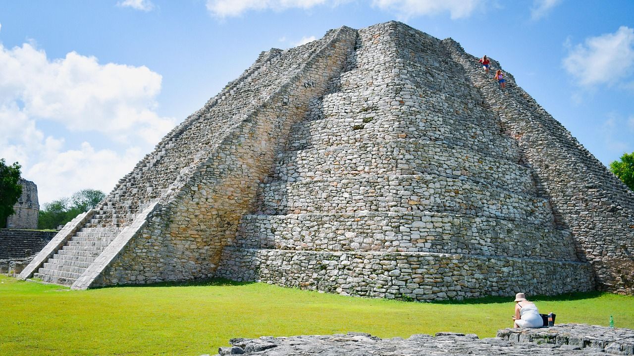 A large stone pyramid is sitting on top of a lush green field.