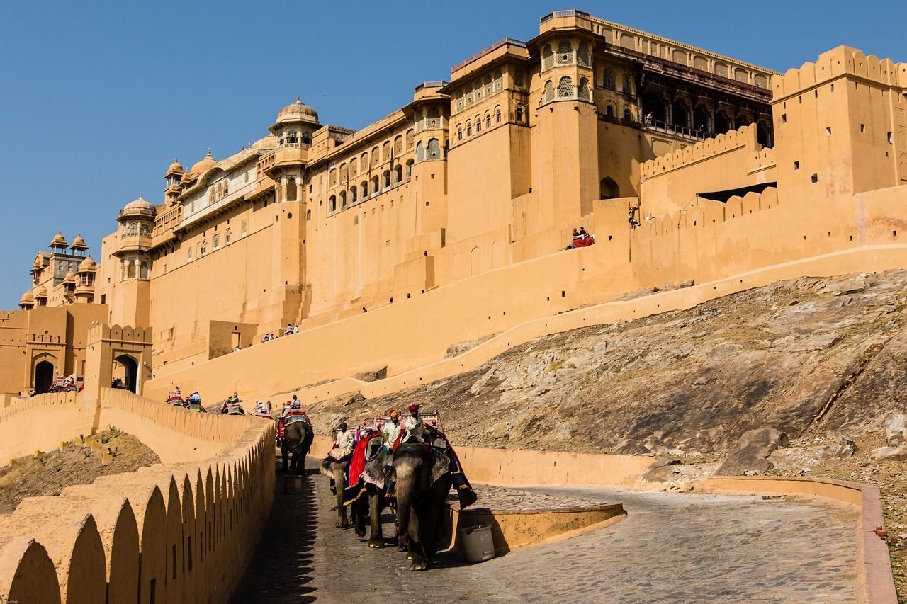 A group of people are riding on the backs of elephants in front of a large building.