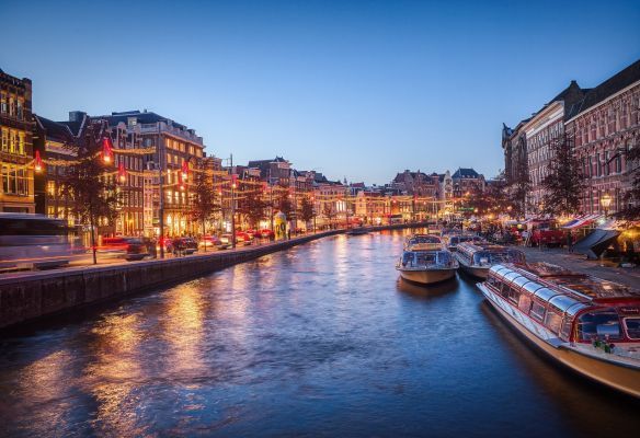 A canal in amsterdam with boats and buildings at night.