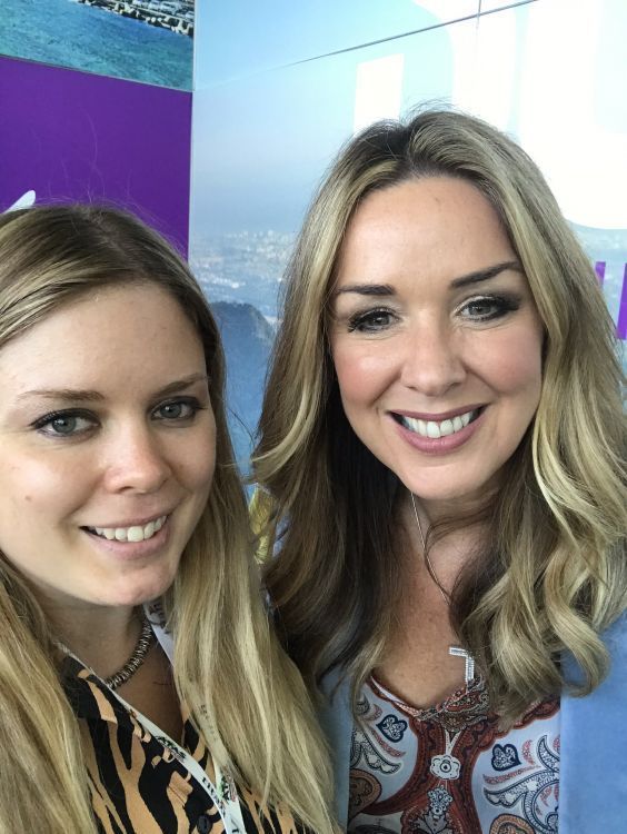 Two women are posing for a picture together and smiling for the camera.