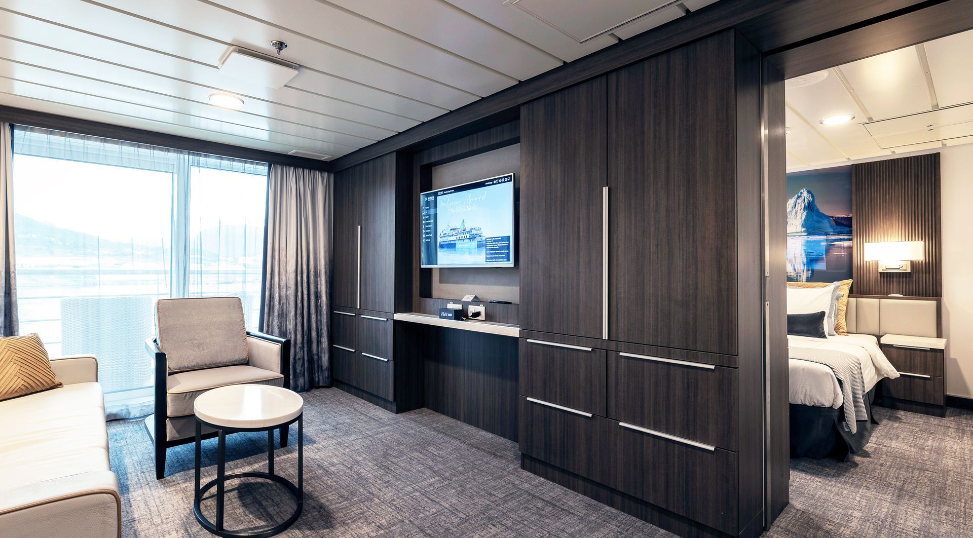 A living room with a couch , chair , table and television in the Captains Suite on Sylvia Earle