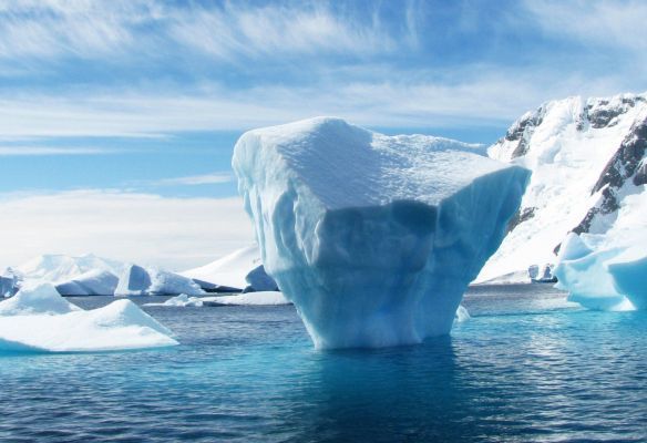 A large iceberg is floating on top of a body of water.