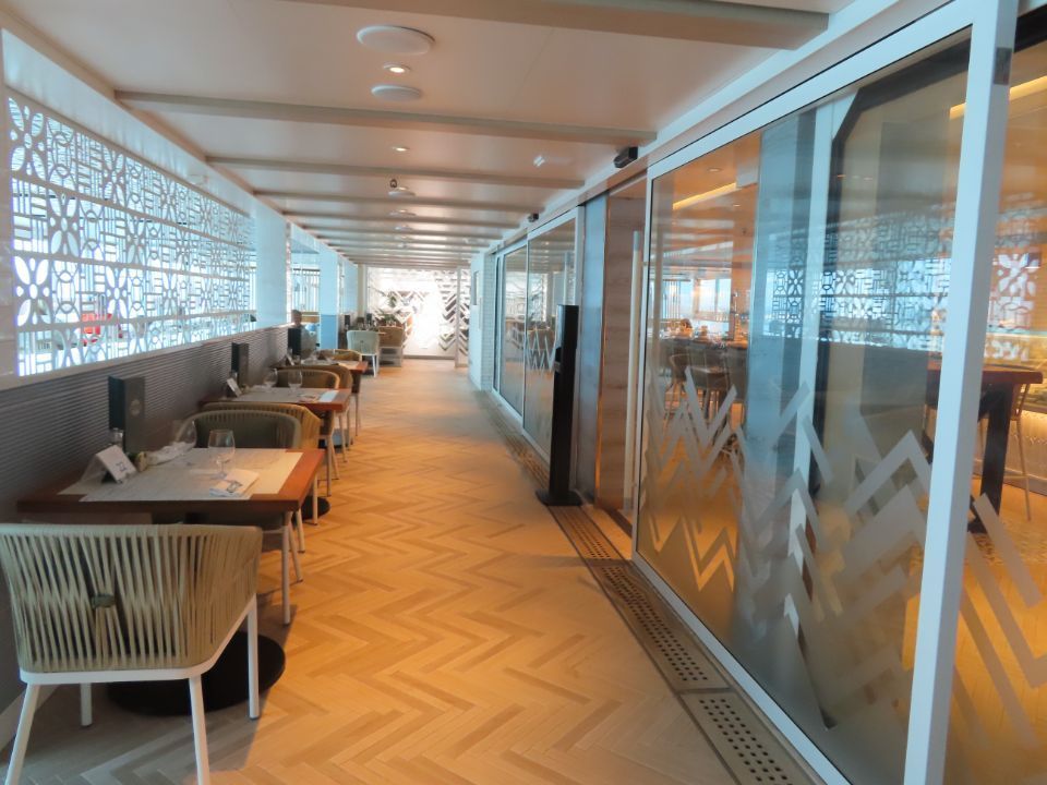 A long hallway with tables and chairs in a restaurant