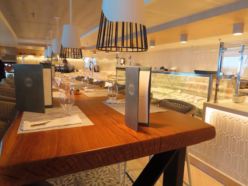 A wooden table in a restaurant with a menu on it