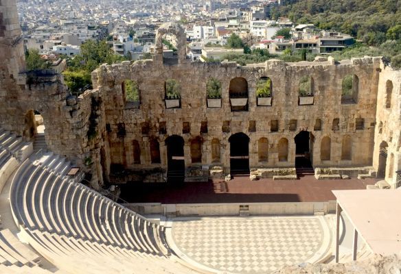 An aerial view of an ancient amphitheater with a city in the background