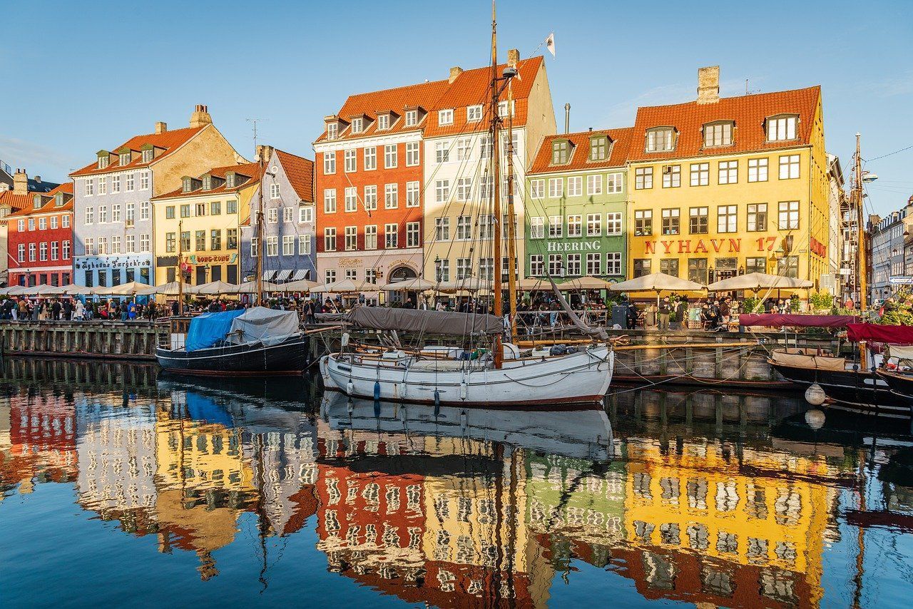 A boat is docked in copenhagen harbor with buildings in the background  on Azamara 2027 World Cruise