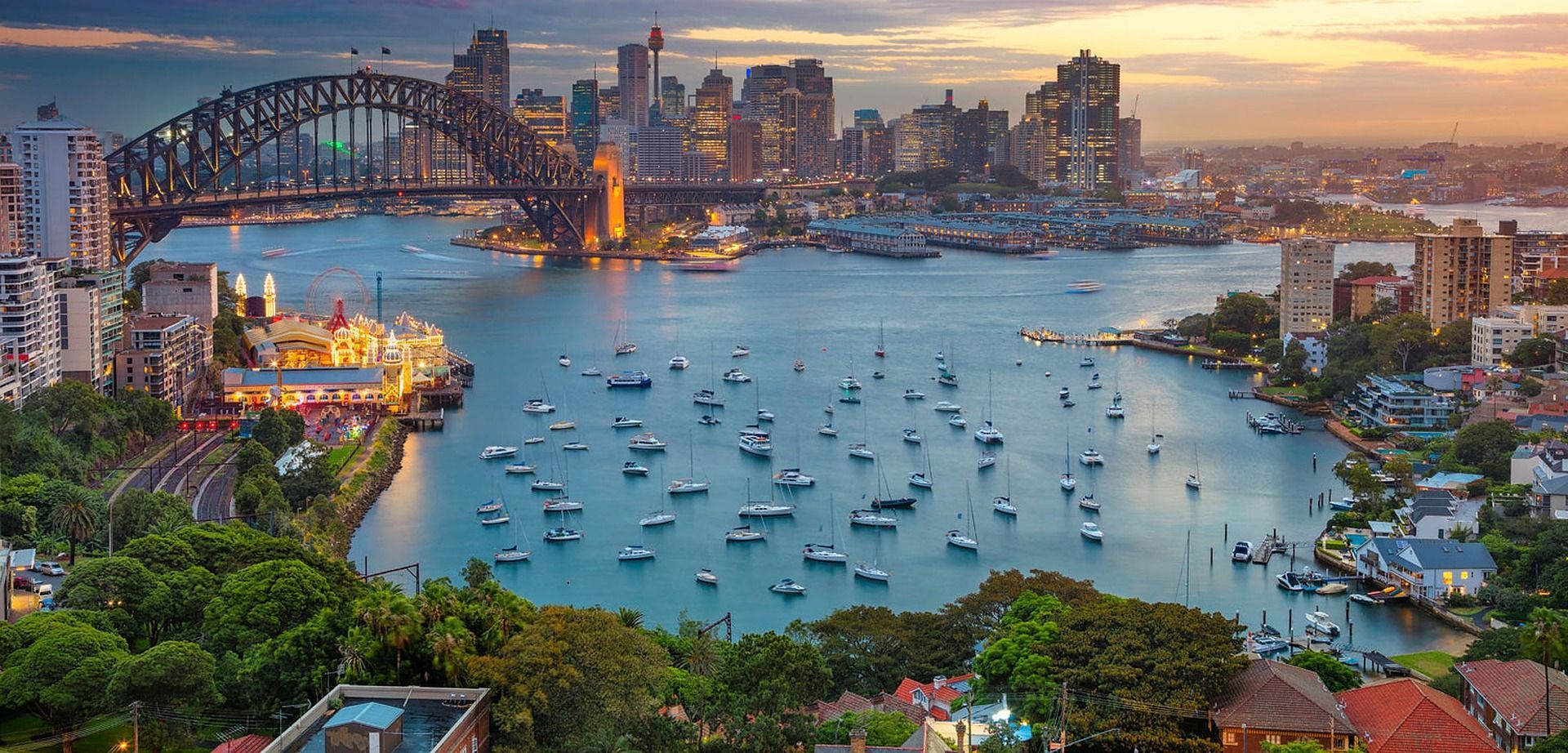 An aerial view of a harbor with boats in it and Sydney city in the background.