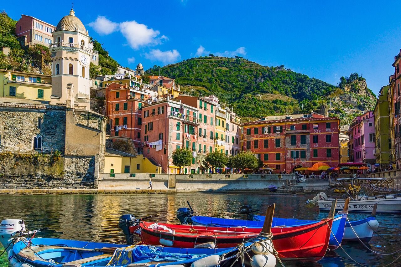 A group of boats are docked in a harbor with buildings in the background.