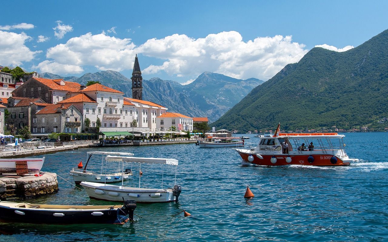 A boat is floating on a lake with mountains in the background in Persat in Montenegro