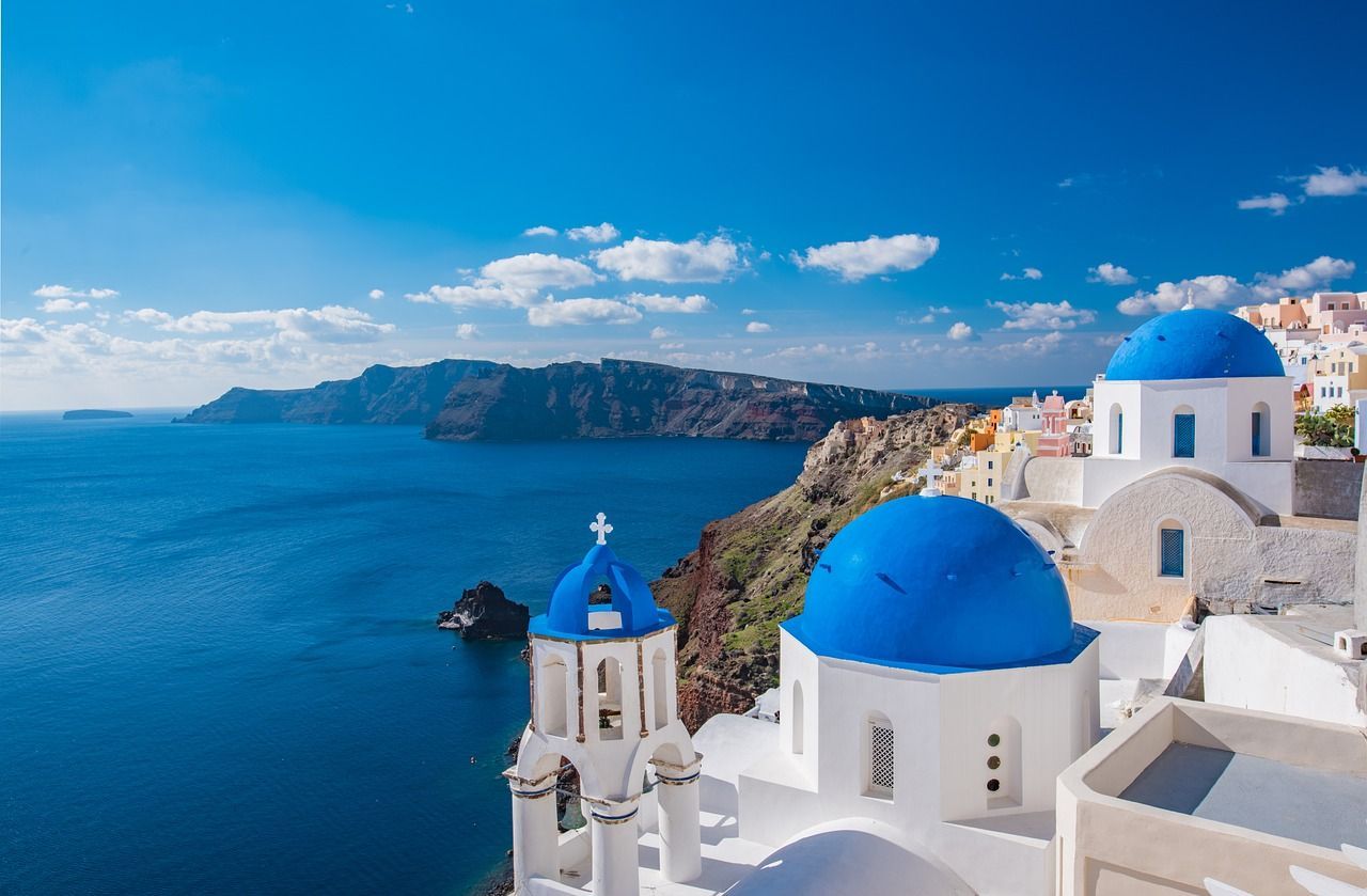 A group of blue and white buildings sitting on top of a hill overlooking the ocean in Oia, Santorini