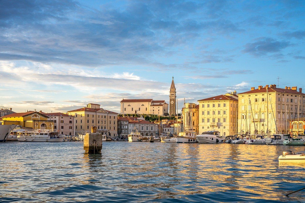 There are many boats in the water in front of a city Piran Slovenia