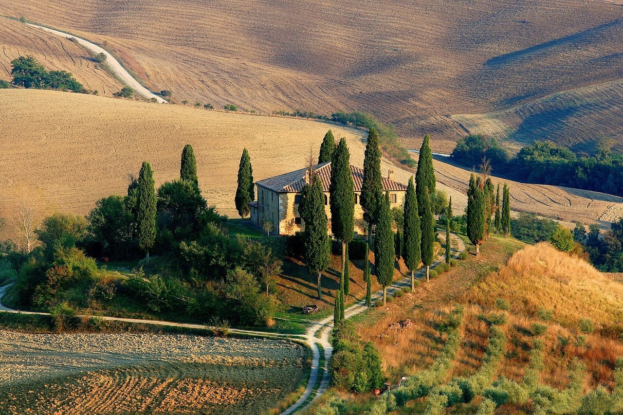 A house sits on top of a hill surrounded by trees in Tuscany