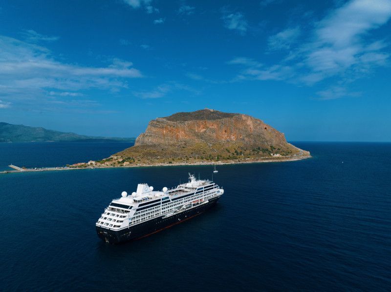 An aerial view of a cruise ship in the ocean near a small island with Azamara written on it