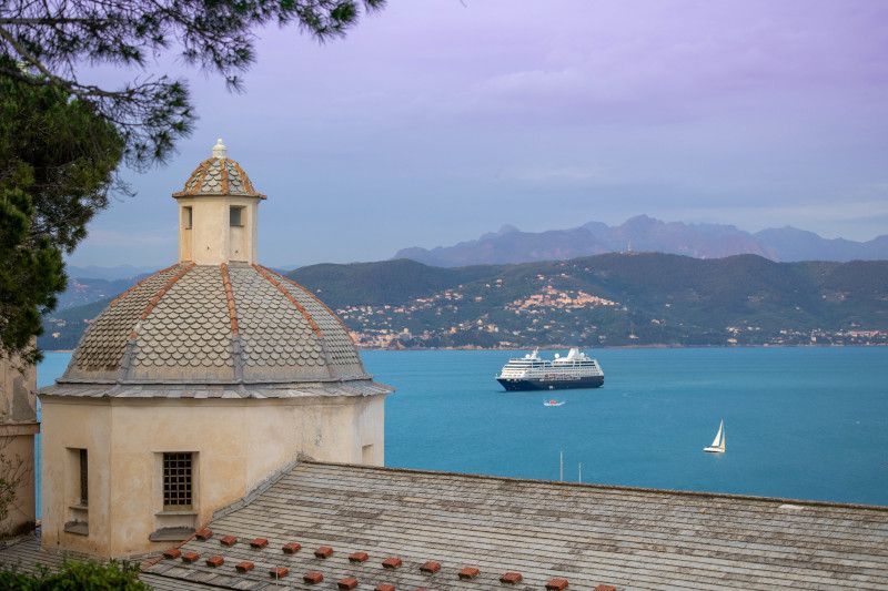 A boat is floating on the water in the distance behind a building.