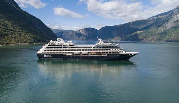 A large cruise ship is floating on top of a lake surrounded by mountains.