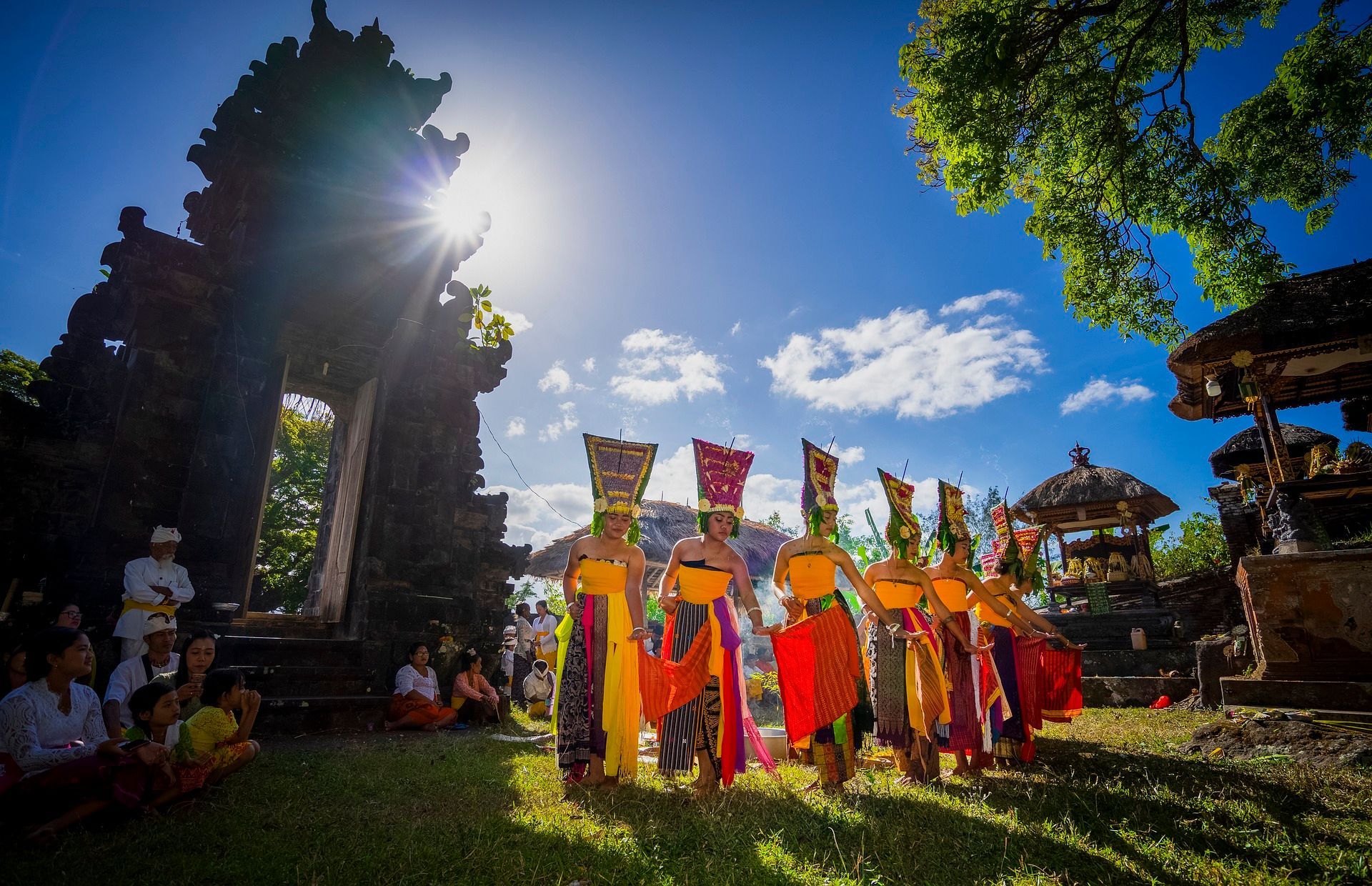 A group of people are standing in a circle in front of a temple in Bali