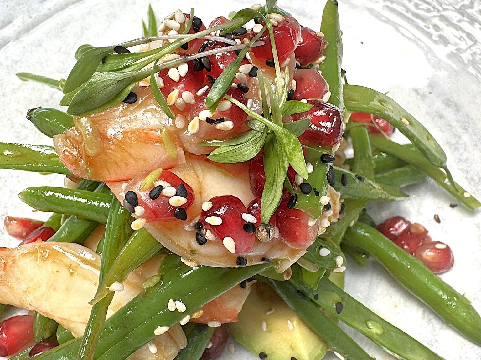 Green bean salad with pomegranate seeds, herbs, and sesame seeds.