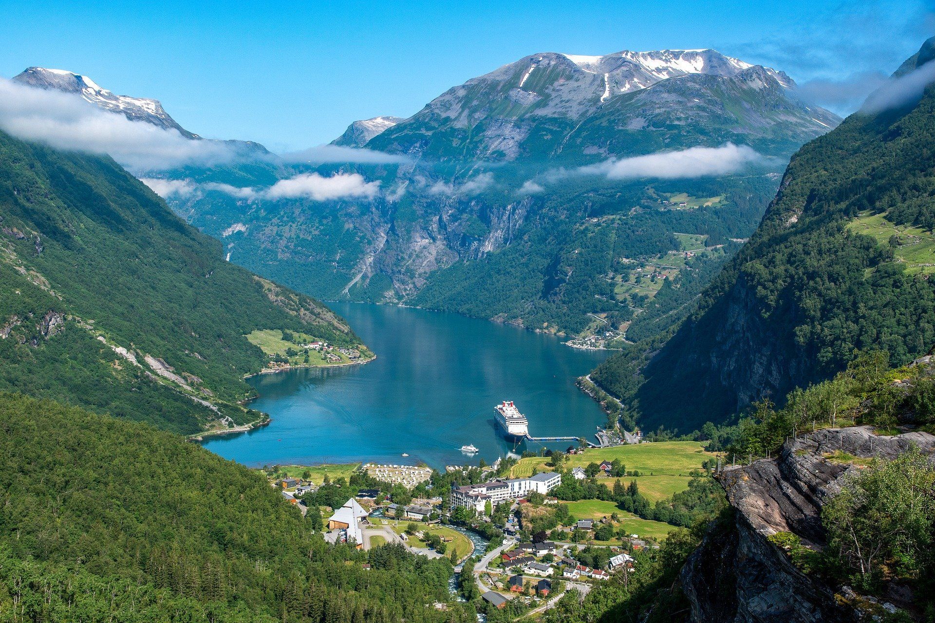 A cruise ship is floating on a lake surrounded by mountains