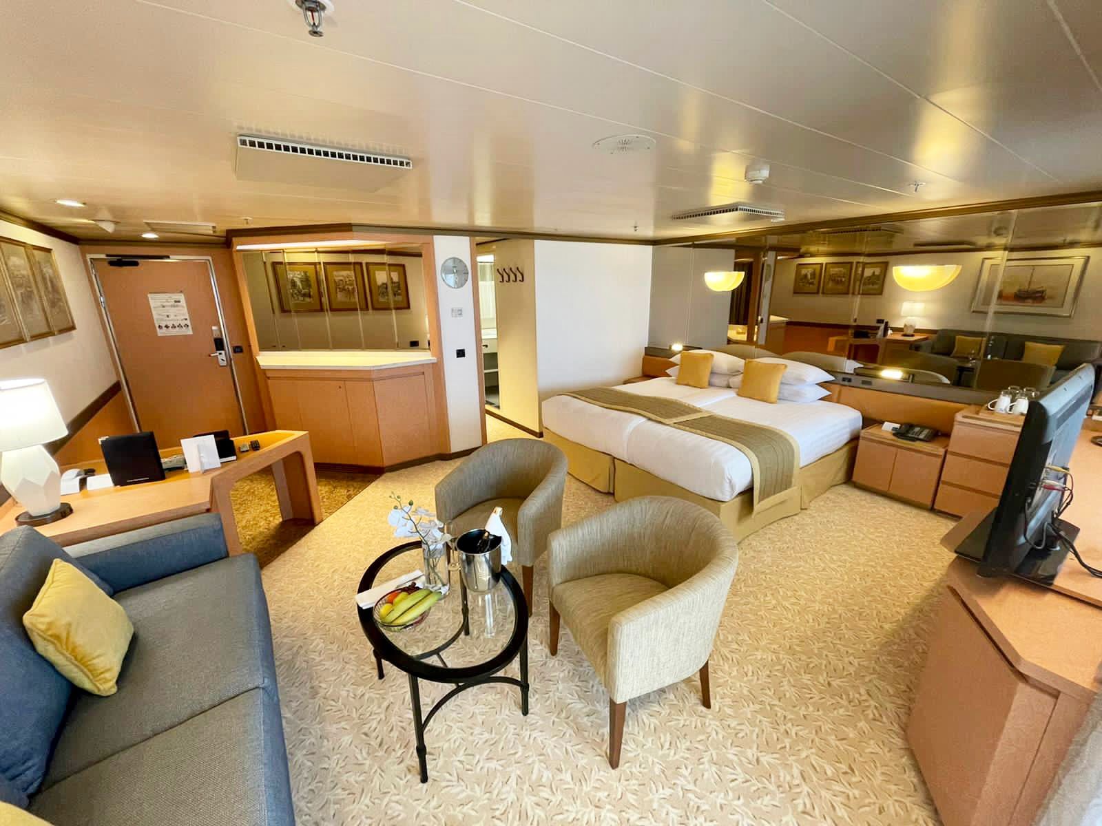 A Premier Suite on a cruise ship with a  couch and a television.