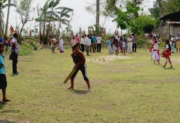 A group of people are playing cricket in a field.