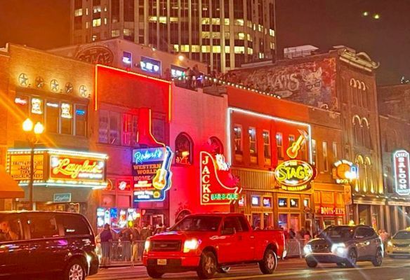 a red truck is driving down a city street at night Broadway Nashville USA