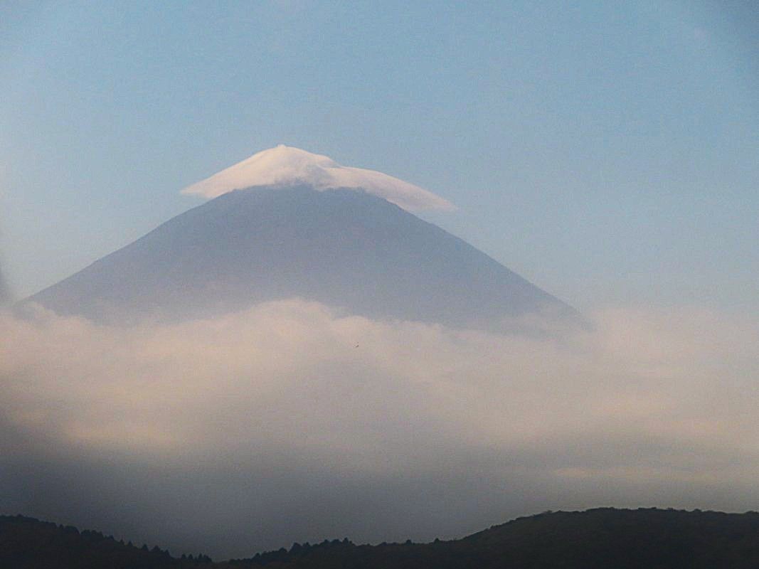 Mountain obscured by clouds, with a small cloud perched on the summit.