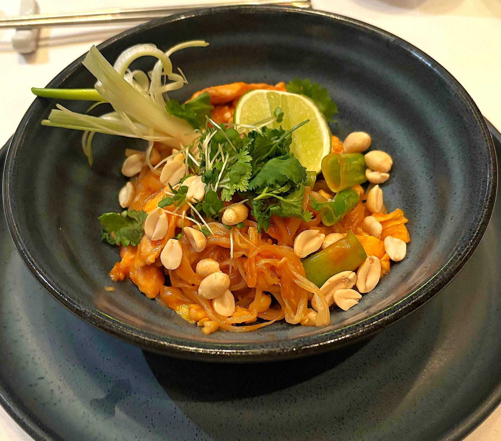 A bowl of food with peanuts and vegetables on a plate.
