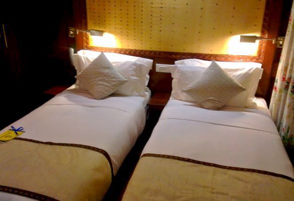 Two beds with white sheets and pillows in a river cruise ship cabin