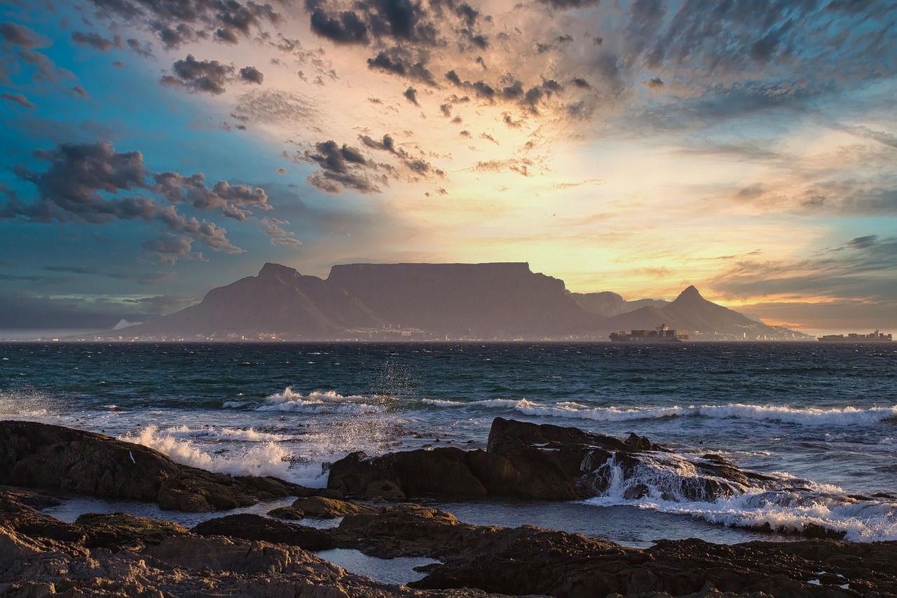 A sunset over the ocean with a mountain in the background.