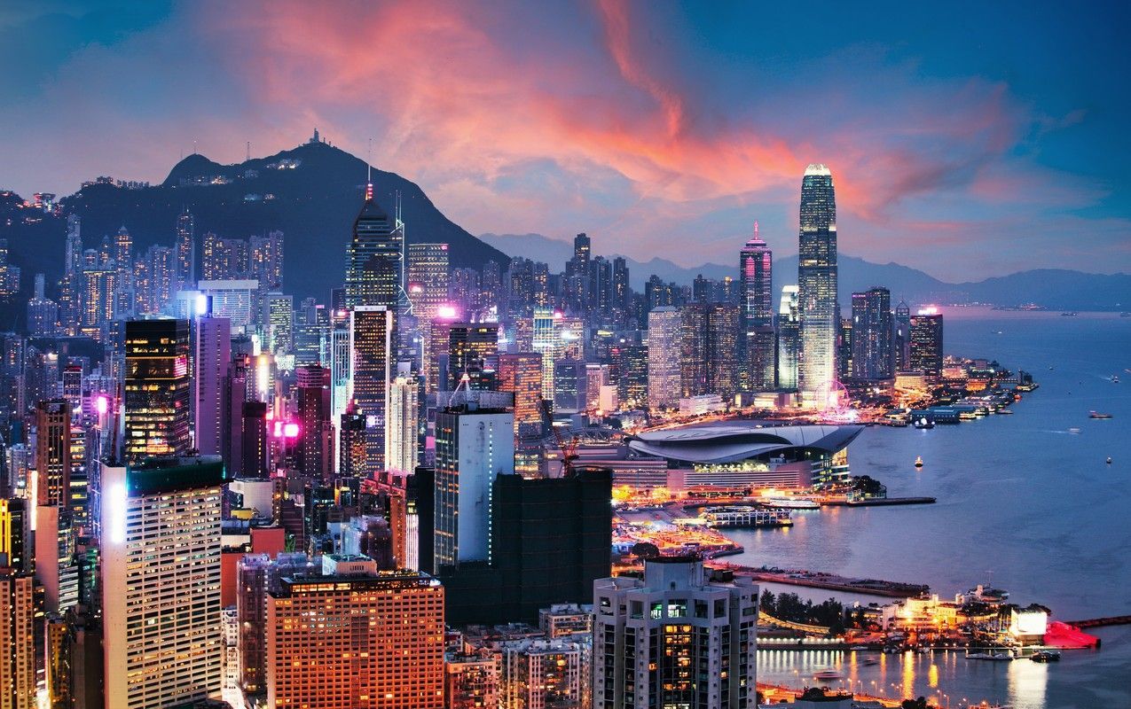 An aerial view of Hong Kong city at night with a mountain in the background