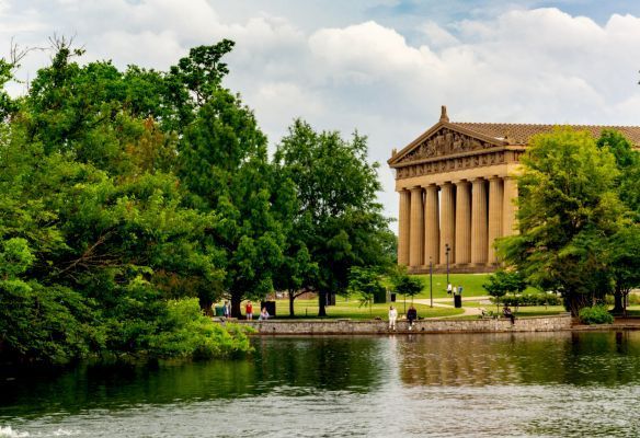 Centennial Park, Nashville USA, a large building with columns is surrounded by trees and a lake .