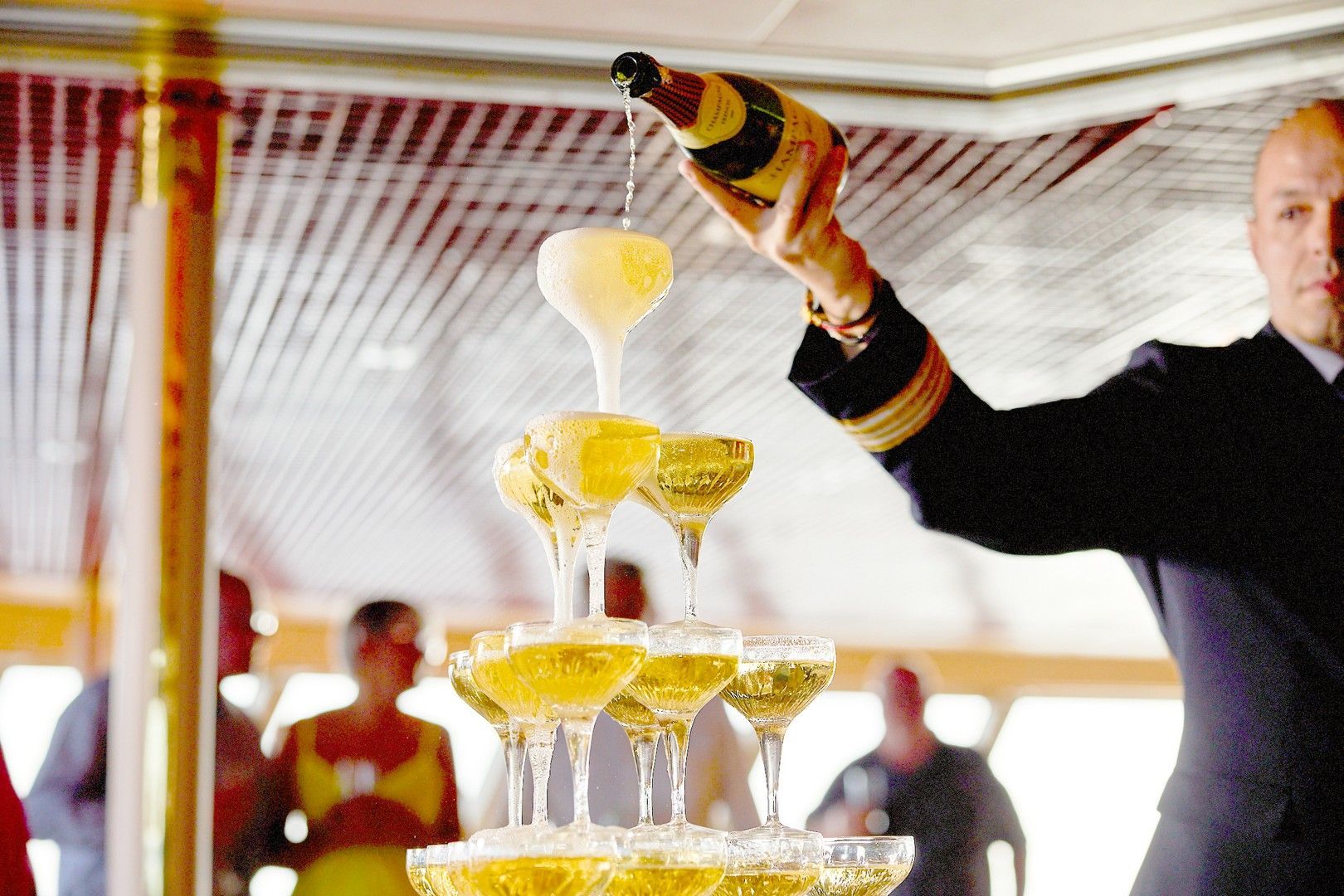 A man is pouring champagne into a pyramid of glasses