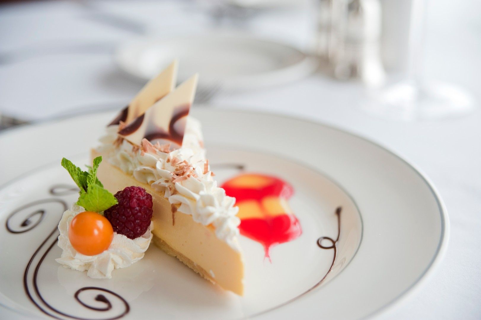 A slice of cheesecake with whipped cream and berries on a white plate.