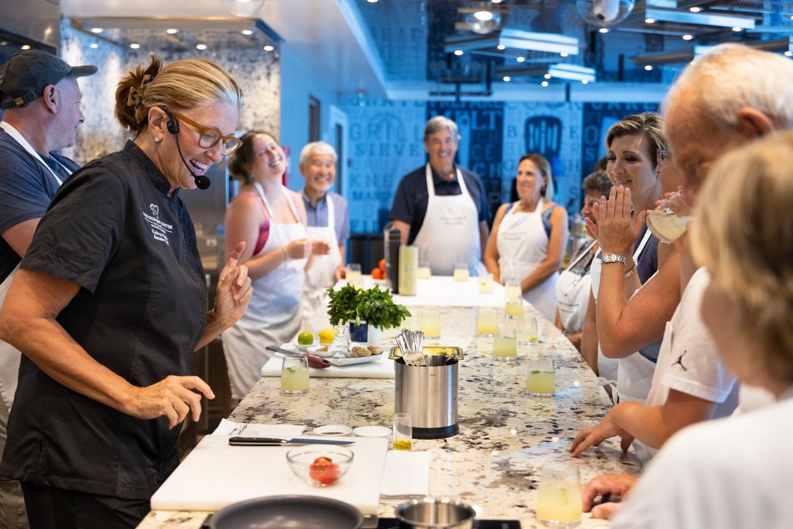 A woman is teaching a group of people how to cook in a kitchen.