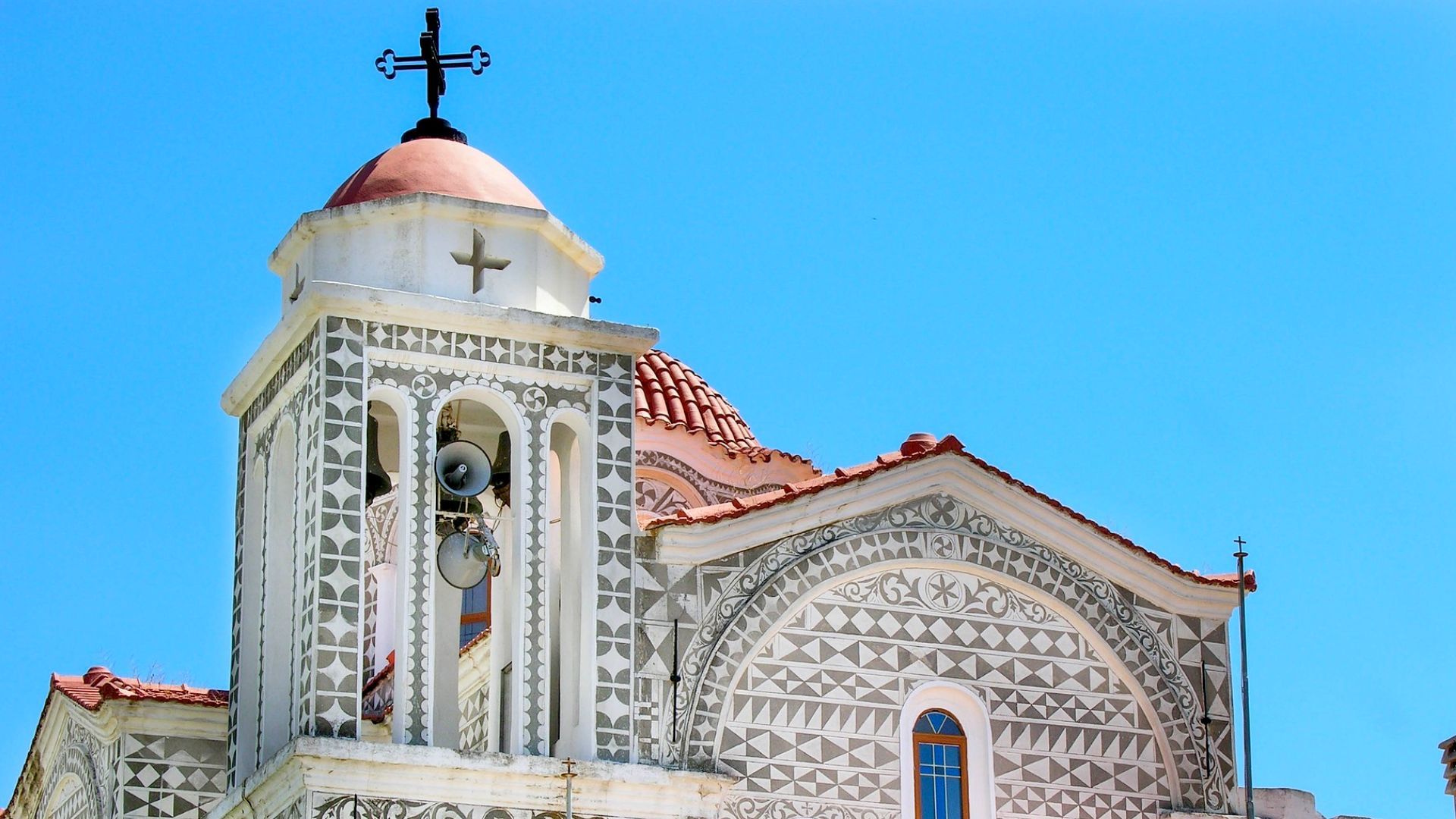 a church with a bell tower and a cross on top of it on Chios, Greece Rouketopolemos World Festival in April